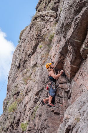 Yuzhnoukrainsk, Ukraine - June 19, 2018: Rock climbing. A young climber climbs a vertical granite rock. Extreme sport. Training of mountaineers.のeditorial素材