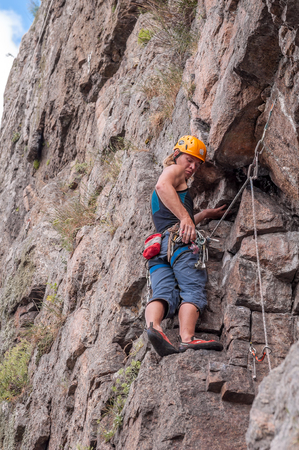 Yuzhnoukrainsk, Ukraine - June 19, 2018: Rock climbing. A young climber climbs a vertical granite rock. Extreme sport. Training of mountaineers.のeditorial素材