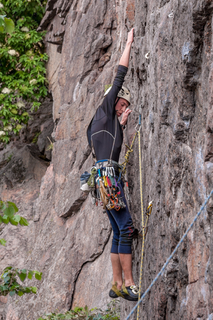 Yuzhnoukrainsk, Ukraine - June 19, 2018: Rock climbing. A young climber climbs a vertical granite rock. Extreme sport. Training of mountaineers.のeditorial素材