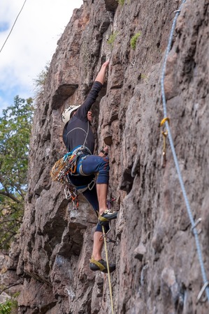 Yuzhnoukrainsk, Ukraine - June 19, 2018: Rock climbing. A young climber climbs a vertical granite rock. Extreme sport. Training of mountaineers.のeditorial素材