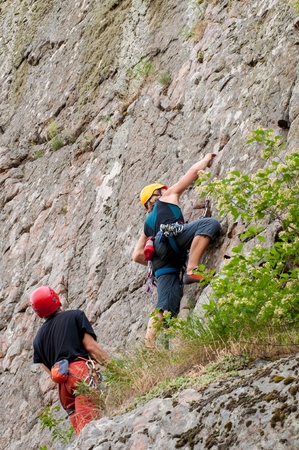 Rock climbing. A group of young rock climbers climb the vertical granite rock. Extreme sport. Training of mountaineersの写真素材