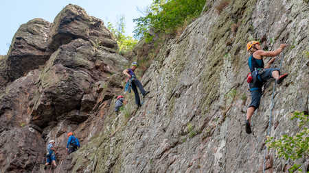 Yuzhnoukrainsk, Ukraine - June 20, 2018: Rock climbing. A group of young rock climbers climb the vertical granite rock. Extreme sport. Training of mountaineersのeditorial素材