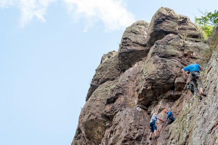 Yuzhnoukrainsk, Ukraine - June 20, 2018: Rock climbing. A group of young rock climbers climb the vertical granite rock. Extreme sport. Training of mountaineersのeditorial素材