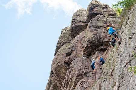 Yuzhnoukrainsk, Ukraine - June 20, 2018: Rock climbing. A group of young rock climbers climb the vertical granite rock. Extreme sport. Training of mountaineersのeditorial素材