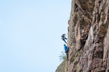 Yuzhnoukrainsk, Ukraine - June 20, 2018: Rock climbing. A group of young rock climbers climb the vertical granite rock. Extreme sport. Training of mountaineersのeditorial素材
