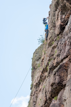 Yuzhnoukrainsk, Ukraine - June 20, 2018: Rock climbing. A group of young rock climbers climb the vertical granite rock. Extreme sport. Training of mountaineersのeditorial素材