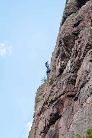 Yuzhnoukrainsk, Ukraine - June 20, 2018: Rock climbing. A group of young rock climbers climb the vertical granite rock. Extreme sport. Training of mountaineersのeditorial素材