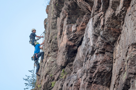 Yuzhnoukrainsk, Ukraine - June 20, 2018: Rock climbing. A group of young rock climbers climb the vertical granite rock. Extreme sport. Training of mountaineersのeditorial素材