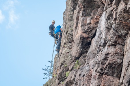 Yuzhnoukrainsk, Ukraine - June 20, 2018: Rock climbing. A group of young rock climbers climb the vertical granite rock. Extreme sport. Training of mountaineersのeditorial素材