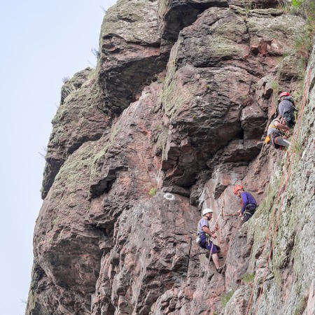 Yuzhnoukrainsk, Ukraine - June 20, 2018: Rock climbing. A group of young rock climbers climb the vertical granite rock. Extreme sport. Training of mountaineersのeditorial素材
