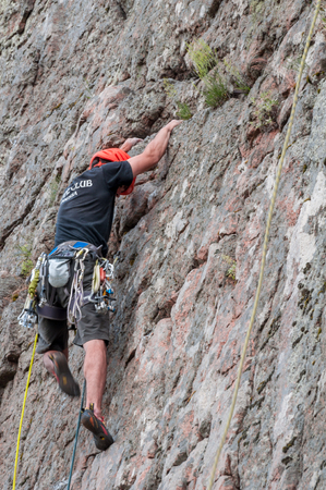 Yuzhnoukrainsk, Ukraine - June 20, 2018: Rock climbing. A young climber climbs a vertical granite rock. Extreme sport. Training of mountaineersのeditorial素材
