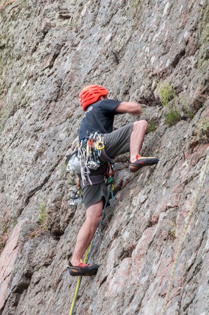 Yuzhnoukrainsk, Ukraine - June 20, 2018: Rock climbing. A young climber climbs a vertical granite rock. Extreme sport. Training of mountaineersのeditorial素材