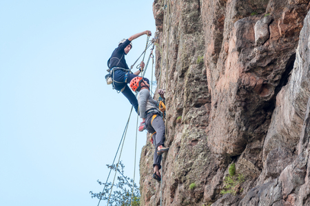 Yuzhnoukrainsk, Ukraine - June 20, 2018: Rock climbing. A group of young rock climbers climb the vertical granite rock. Extreme sport. Training of mountaineersのeditorial素材
