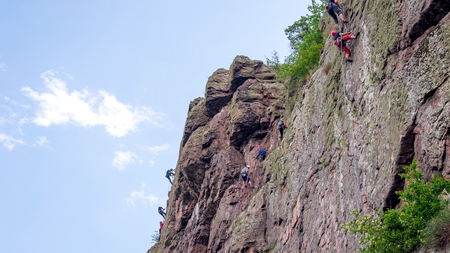 Yuzhnoukrainsk, Ukraine - June 20, 2018: Rock climbing. A group of young rock climbers climb the vertical granite rock. Extreme sport. Training of mountaineersのeditorial素材