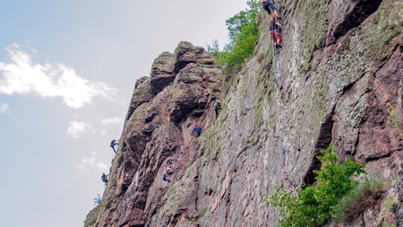Yuzhnoukrainsk, Ukraine - June 20, 2018: Rock climbing. A group of young rock climbers climb the vertical granite rock. Extreme sport. Training of mountaineersのeditorial素材