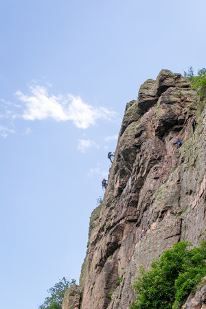 Yuzhnoukrainsk, Ukraine - June 20, 2018: Rock climbing. A group of young rock climbers climb the vertical granite rock. Extreme sport. Training of mountaineersのeditorial素材