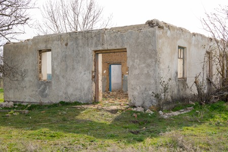 The ruins of an old earthen house without a roof. Holes in the wall at the site of windows and doors