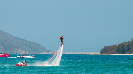 Hainan, Sanya, China - May 14, 2019: Flyboarding. Flying over the water on the board with a powerful jet of water. Attraction on the beach. Extreme sport and recreationのeditorial素材