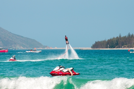 Hainan, Sanya, China - May 14, 2019: Flyboarding. Flying over the water on the board with a powerful jet of water. Attraction on the beach. Extreme sport and recreationのeditorial素材