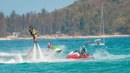 Hainan, Sanya, China - May 14, 2019: Flyboarding. Flying over the water on the board with a powerful jet of water. Attraction on the beach. Extreme sport and recreationのeditorial素材