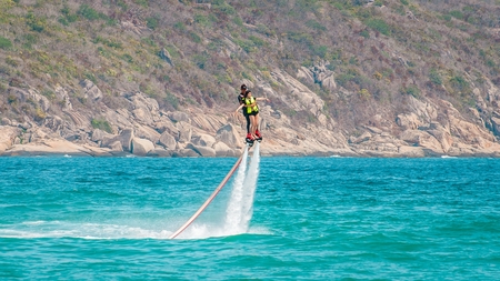 Hainan, Sanya, China - May 14, 2019: Flyboarding. Flying over the water on the board with a powerful jet of water. Attraction on the beach. Extreme sport and recreationのeditorial素材