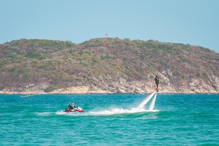 Hainan, Sanya, China - May 14, 2019: Flyboarding. Flying over the water on the board with a powerful jet of water. Attraction on the beach. Extreme sport and recreationのeditorial素材