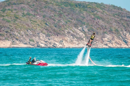 Hainan, Sanya, China - May 14, 2019: Flyboarding. Flying over the water on the board with a powerful jet of water. Attraction on the beach. Extreme sport and recreationのeditorial素材