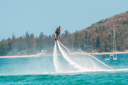 Hainan, Sanya, China - May 14, 2019: Flyboarding. Flying over the water on the board with a powerful jet of water. Attraction on the beach. Extreme sport and recreationのeditorial素材