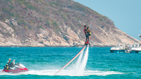 Hainan, Sanya, China - May 14, 2019: Flyboarding. Flying over the water on the board with a powerful jet of water. Attraction on the beach. Extreme sport and recreationのeditorial素材