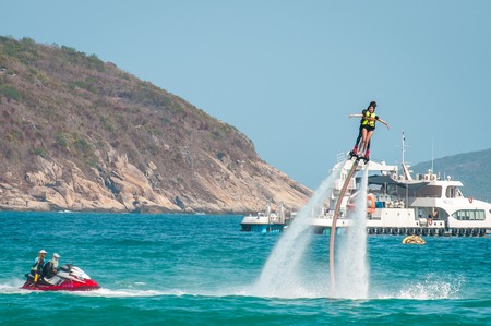Hainan, Sanya, China - May 14, 2019: Flyboarding. Flying over the water on the board with a powerful jet of water. Attraction on the beach. Extreme sport and recreationのeditorial素材