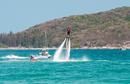 Hainan, Sanya, China - May 14, 2019: Flyboarding. Flying over the water on the board with a powerful jet of water. Attraction on the beach. Extreme sport and recreationのeditorial素材