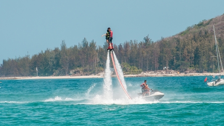Hainan, Sanya, China - May 14, 2019: Flyboarding. Flying over the water on the board with a powerful jet of water. Attraction on the beach. Extreme sport and recreationのeditorial素材