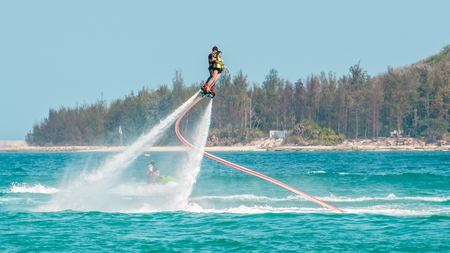 Hainan, Sanya, China - May 14, 2019: Flyboarding. Flying over the water on the board with a powerful jet of water. Attraction on the beach. Extreme sport and recreationのeditorial素材