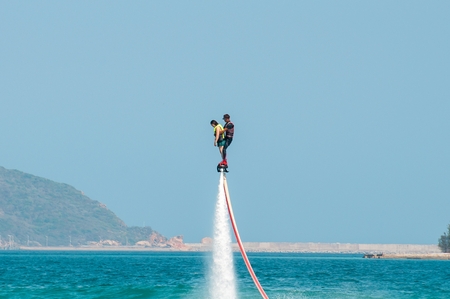 Hainan, Sanya, China - May 14, 2019: Flyboarding. Flying over the water on the board with a powerful jet of water. Attraction on the beach. Extreme sport and recreationのeditorial素材