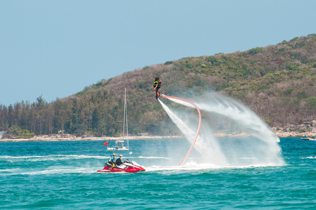 Hainan, Sanya, China - May 14, 2019: Flyboarding. Flying over the water on the board with a powerful jet of water. Attraction on the beach. Extreme sport and recreationのeditorial素材