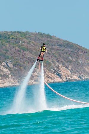 Hainan, Sanya, China - May 14, 2019: Flyboarding. Flying over the water on the board with a powerful jet of water. Attraction on the beach. Extreme sport and recreationのeditorial素材