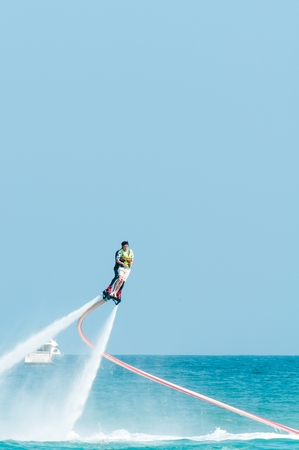 Hainan, Sanya, China - May 14, 2019: Flyboarding. Flying over the water on the board with a powerful jet of water. Attraction on the beach. Extreme sport and recreationのeditorial素材