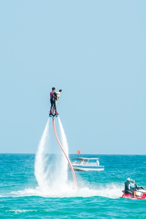 Hainan, Sanya, China - May 14, 2019: Flyboarding. Flying over the water on the board with a powerful jet of water. Attraction on the beach. Extreme sport and recreationのeditorial素材
