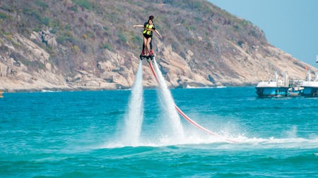 Hainan, Sanya, China - May 14, 2019: Flyboarding. Flying over the water on the board with a powerful jet of water. Attraction on the beach. Extreme sport and recreationのeditorial素材