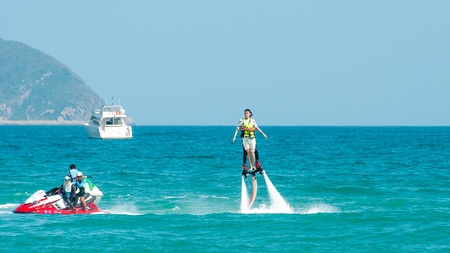 Hainan, Sanya, China - May 14, 2019: Flyboarding. Flying over the water on the board with a powerful jet of water. Attraction on the beach. Extreme sport and recreationのeditorial素材