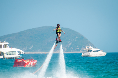 Hainan, Sanya, China - May 14, 2019: Flyboarding. Flying over the water on the board with a powerful jet of water. Attraction on the beach. Extreme sport and recreationのeditorial素材