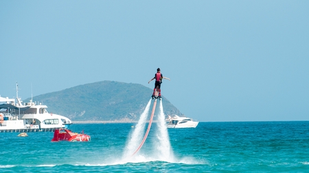 Hainan, Sanya, China - May 14, 2019: Flyboarding. Flying over the water on the board with a powerful jet of water. Attraction on the beach. Extreme sport and recreationのeditorial素材