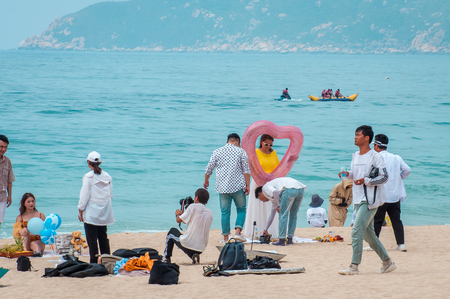 Hainan Island, Sanya city, China - May 14, 2019: Yalong Bay beach. Backstage wedding photo session of Chinese couples. Newlyweds posing for a wedding photo shoot. Backstage photo session love storyのeditorial素材