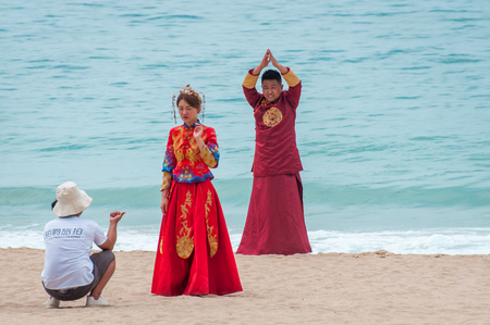 Hainan Island, Sanya city, China - May 14, 2019: Yalong Bay beach. Backstage wedding photo session of Chinese couples. Newlyweds posing for a wedding photo shoot. Backstage photo session love storyのeditorial素材