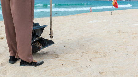 Hainan Island, Sanya, China - May 16, 2019: A cleaning lady picks up trash on Hainan Beach with special handy forcepsの写真素材