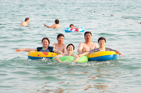 Hainan, China - May 16, 2019: A cheerful group of unidentified Chinese people are relaxing in the water on the beach of Dudonghai. The Chinese do not swim well, so they often go to sea with lifebuoysのeditorial素材