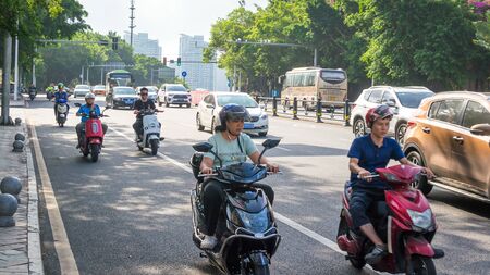 Sanya, Hainan island, China - May 15, 2019: Road traffic. A lot of electric cars. Hybrid buses. 90 percent of mopeds are electric. From 2030, only electric transport will be allowed on the island.のeditorial素材