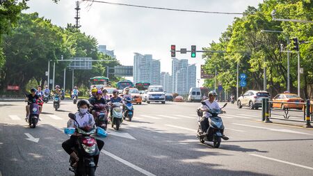 Sanya, Hainan island, China - May 15, 2019: Road traffic. A lot of electric cars. Hybrid buses. 90 percent of mopeds are electric. From 2030, only electric transport will be allowed on the island.のeditorial素材