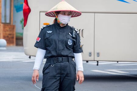 Haikou, Hainan, China - May 11, 2019: Service staff in the park of an extinct volcano Rock Hill Volcanoe Haikou. Chinese woman in uniform, working clothes rangers.のeditorial素材