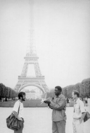 Paris, old black and white photo, august 1994. A black street vendor is trying to sell a toy airplane to Ukrainian tourists. On the background Eiffel Towerの写真素材